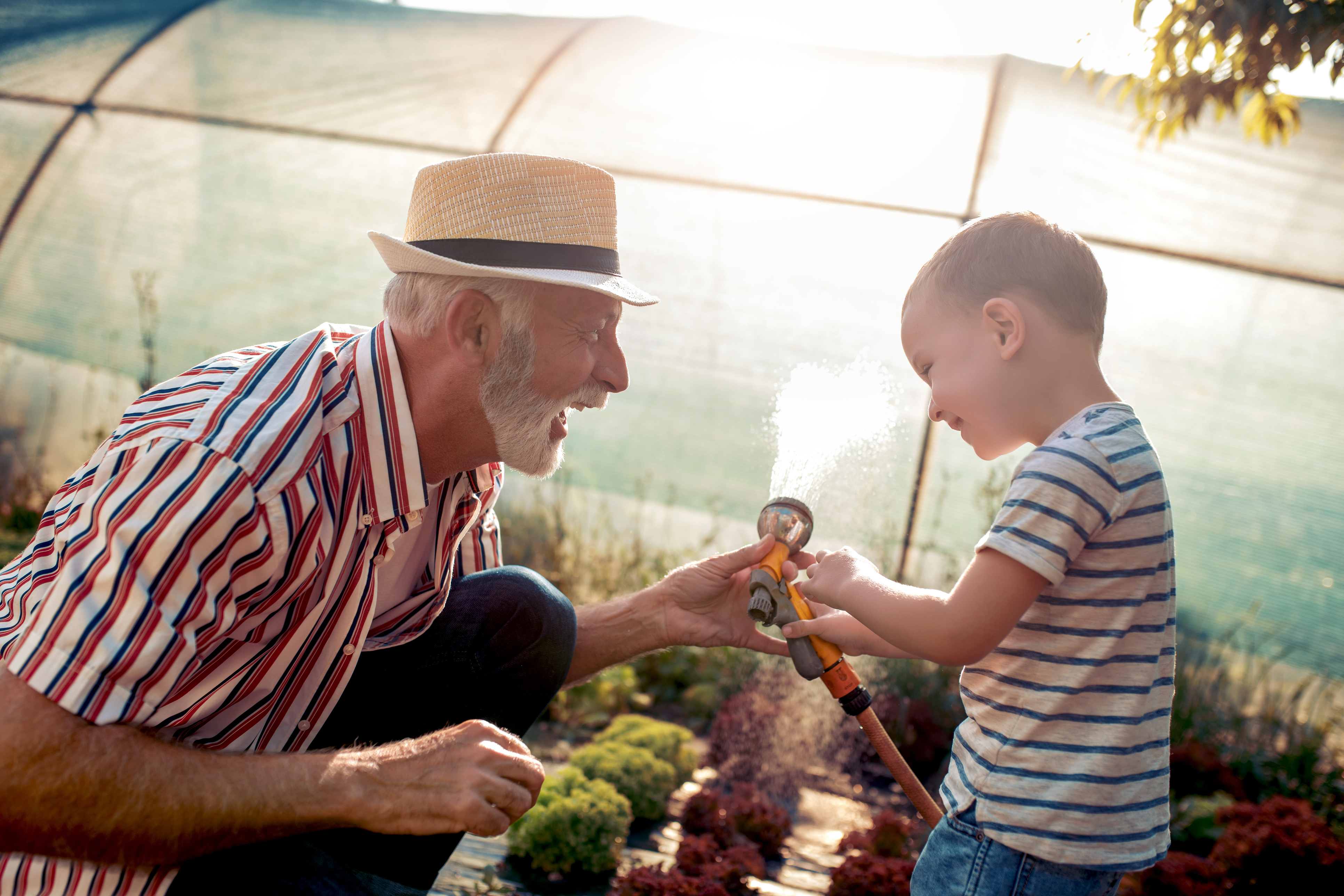 Grandfather and grandson watering a garden