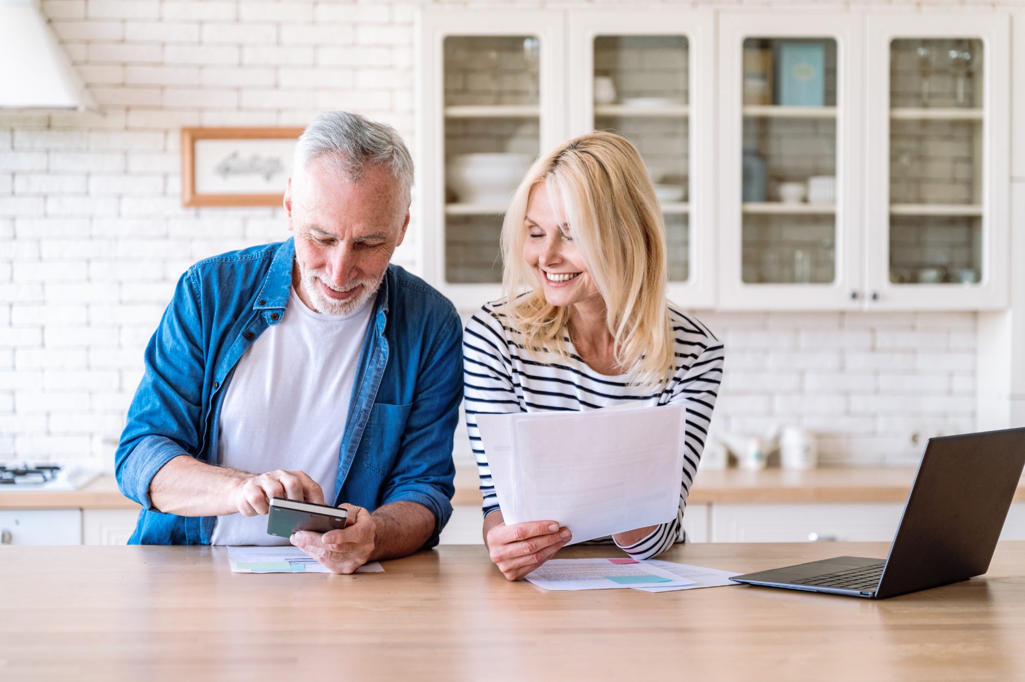 A couple reviewing paperwork at a kitchen counter